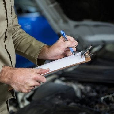 Mid-section of mechanic preparing a check list in repair garage