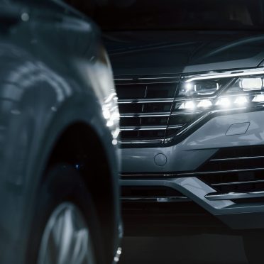 Powerful headlights. Particle view of modern luxury cars parked indoors at daytime.